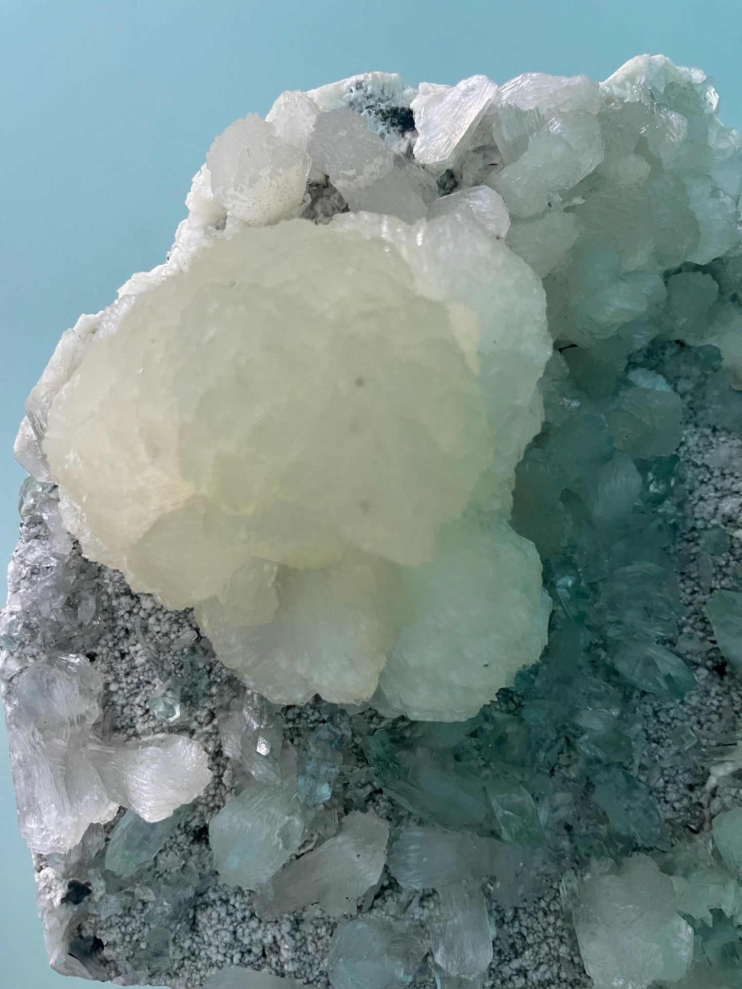 pointed light green apophyllite crystal with stilbite