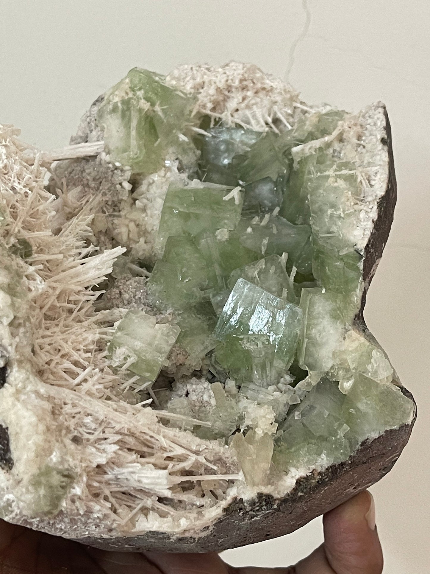 Green apophyllite crystal with scolecite sprays base geode